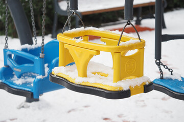 Bright yellow swing covered in snow during winter playtime