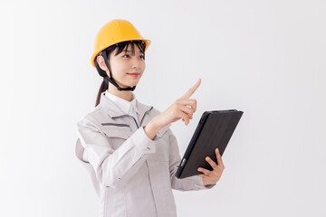 タブレットを使用しながら指差しをする作業服の女性
