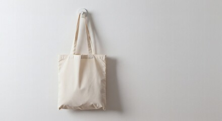 Minimalist white tote bag hanging neatly from a simple wall hook on a clean white background, soft natural lighting, shadow detail, modern and elegant composition