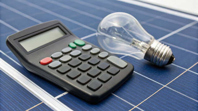 Calculator and light bulb on solar panel symbolize renewable energy and oil price impact. Oil price and renewable energy concept. economic effect, energy security, financial market connection.