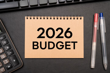 2026 BUDGET text on Notebook with calculator and office supplies. Budget planning concept.