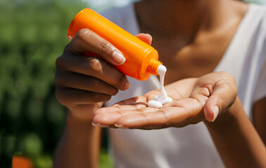 Asian woman's hand close-up squeezing sunscreen onto palm. Preparing for sun protection before sun exposure. Skincare routine for healthy skin