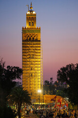 Elevated sunset street view of market stalls at Jemaa el-Fnaa in the Old Town Medina area of Marrakech with 12th century Koutoubia Mosque in the background, west Morocco 