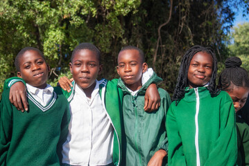 Real photo of cheerful African kids in school uniforms, enjoying time together outdoors. A natural moment full of smiles, youth, friendship, and positive energy. 
