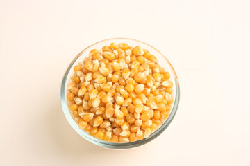 Popcorn seeds in transparent bowl on white background