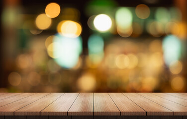 Empty wooden table top with lights bokeh on blur restaurant background.