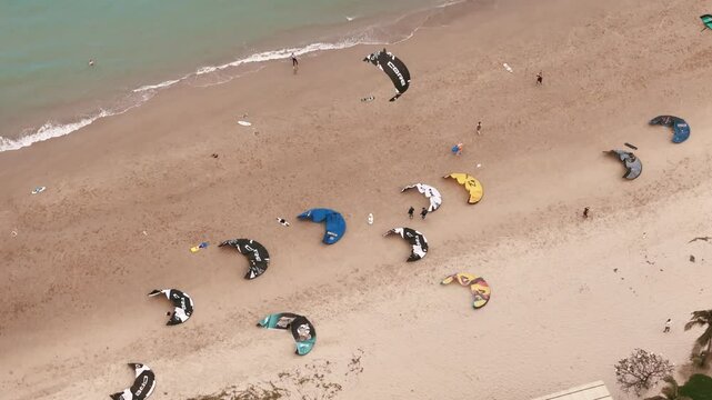 Aerial top view of kiteboarding gear and instructors offering kitesurfing lessons on sandy beach 