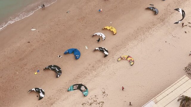 Aerial top view of kiteboarding gear and instructors offering kitesurfing lessons on sandy beach 