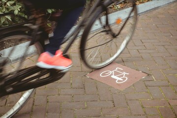 Cyclist front wheel and foot are pedaling on flat design brick-paved lane with white bike marking