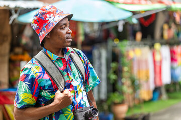 A cheerful tourist in a vibrant shirt walks through a Thai street market, enjoying the atmosphere and connecting with local culture