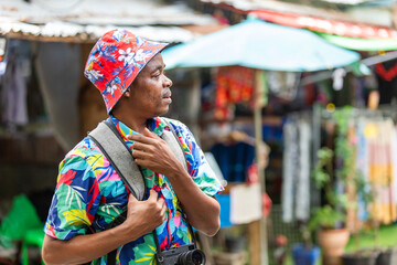 A cheerful tourist in a vibrant shirt walks through a Thai street market, enjoying the atmosphere and connecting with local culture