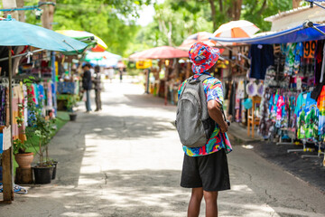 A cheerful tourist in a vibrant shirt walks through a Thai street market, enjoying the atmosphere and connecting with local culture