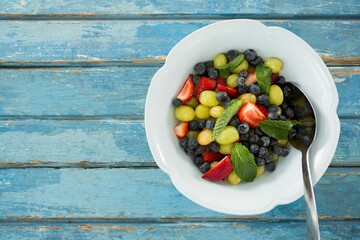 Fresh salad in bowl on blue wooden table © vectorfusionart
