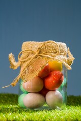 Easter eggs in jar on field