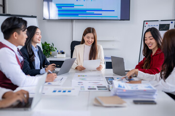 Asian business team analyzing charts and reports in modern office meeting room