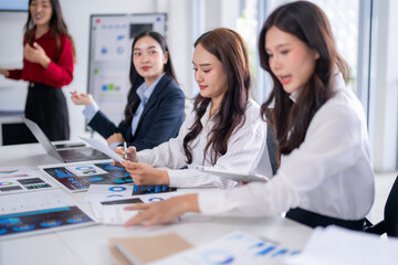 Fototapeta premium Businesswomen working together analyzing financial charts and documents in office meeting room