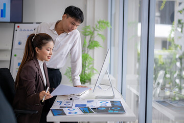 Asian business people analyzing financial charts and graphs, working together in modern office