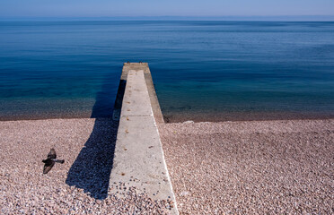 A concrete breakwater pier in a calm sea on a summer day.