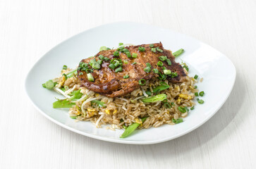 A savory dish of teriyaki-flavored chicken over a bed of fried rice mixed with fresh vegetables