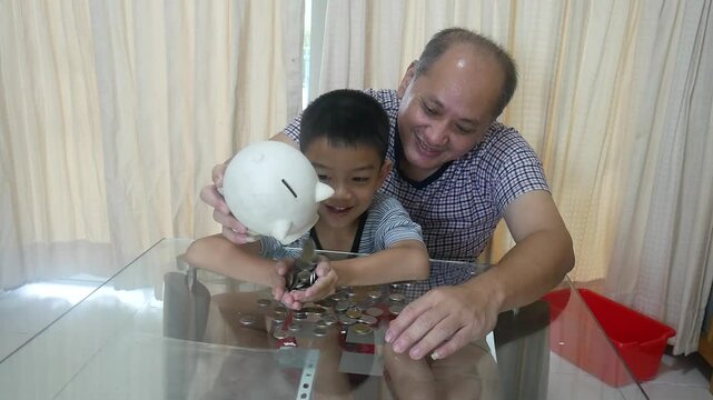 Father and son put coins into a piggy bank together.