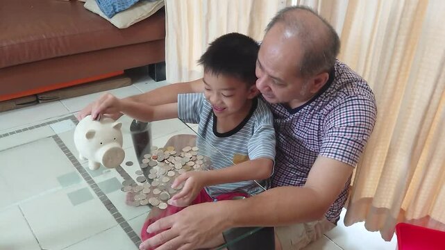Father and son put coins into a piggy bank together.