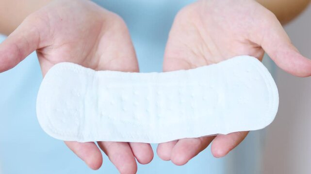 Female hand gripping feminine hygiene product menstrual pad, highlighting personal care during menstrual cycle, supporting comfort and wellness for women's health needs