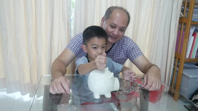 Father and son put coins into a piggy bank together.