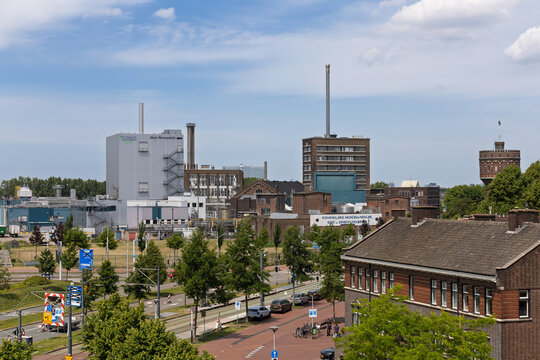 A large industrial complex in Delft featuring a modern DSM-Firmenich facility and other factory buildings under a cloudy sky, representing global industry. Delft, Netherlands, 31 May 2025.