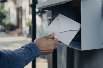 Person posting letter into mailbox close up background..