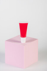 Red lipstick, small tube, and empty space with props on white background.