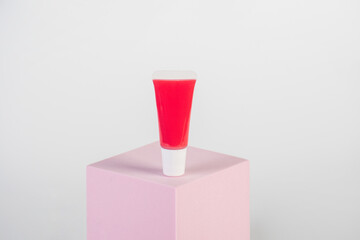 Red lipstick, small tube, and empty space with props on white background.