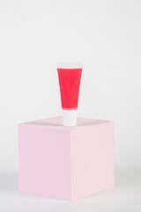 Red lipstick, small tube, and empty space with props on white background.