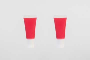 Red lipstick, small tube, and empty space on white background.