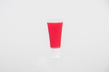 Red lipstick, small tube, and empty space on white background.