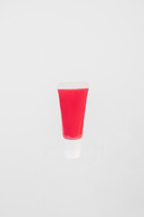 Red lipstick, small tube, and empty space on white background.