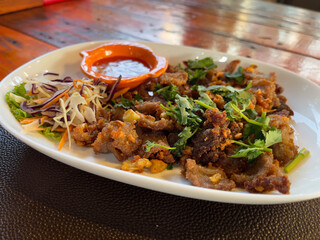 Thai style fried pork with spicy sauce and vegetable on the table