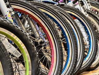 Collection of colorful bicycle wheels displayed together in a vibrant market setting during a sunny...