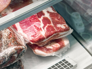 Savory cuts of pork belly displayed in a butcher case at a local market in the early afternoon sunlight