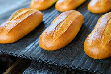 Freshly baked bread rolls emerge from the bakery oven, offering warmth and inviting aromas to everyone nearby
