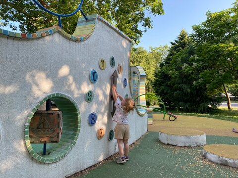 Colorful playground clock wall with a child playing. Educational design for public play areas encouraging interactive learning and exploration.