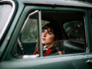 Woman gazes from vintage car window.