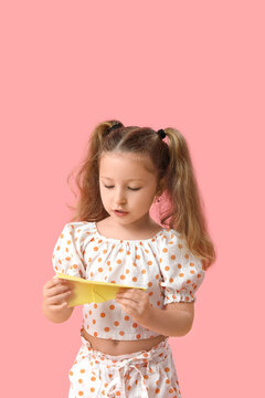 Fototapeta Cute little girl with paper plane on pink background
