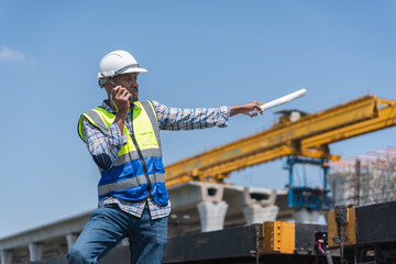 African American Engineer Directing Work on Construction Project, Foreman with Plans and Radio at...