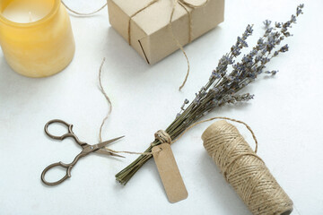 Tied box with scissors, candle and dried lavender on white grunge background