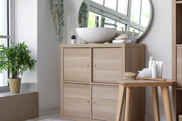 Interior of light bathroom with sink bowl on wooden cabinet and mirror