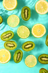 Different fruit slices in water on turquoise background