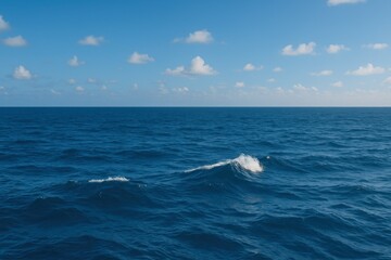 Tranquil Ocean Waves Under a Blue Sky with Floating Clouds Captured in a Serene Coastal Landscape