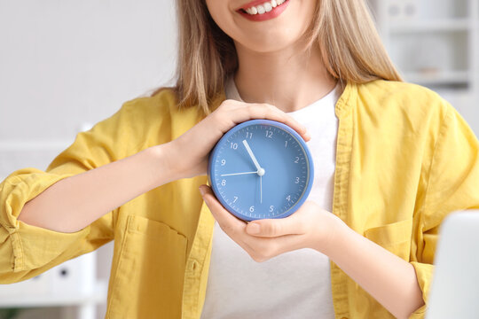 Young businesswoman with alarm clock in office, closeup - Powered by Adobe