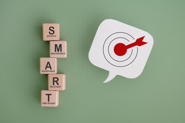 Smart goal for business strategy concept. SMART for specific, measurable, achievable, relevant and time-bound text on wooden block with dartboard on real speech bubble paper cut