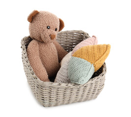 Wicker basket with teddy bear and cushion isolated on white background